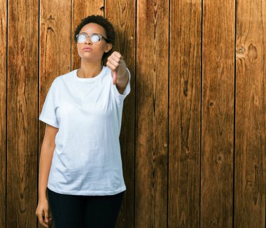 Mutsuz ve kızgın ret gösterilen ve başparmak aşağı hareketi ile negatif seyir izole arka plan üzerinde gözlük güzel genç Afro-Amerikan kadın. Kötü ifade.