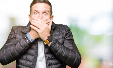 Yakışıklı adam ağız hata için elleriyle kapsayan şok bir kış palto giyiyor. Gizli kavramı.