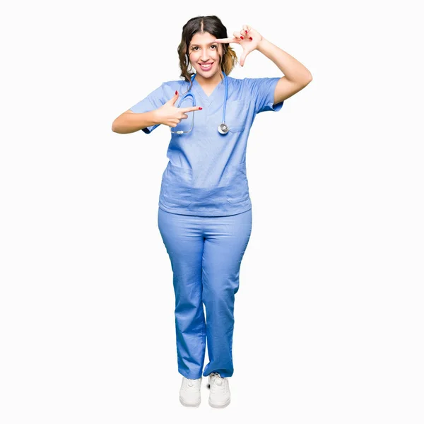 アダルト女医女性医療制服姿で微笑む幸せそうな顔で指と手作りフレームを身に着けています 創造性と写真のコンセプト — ストック写真