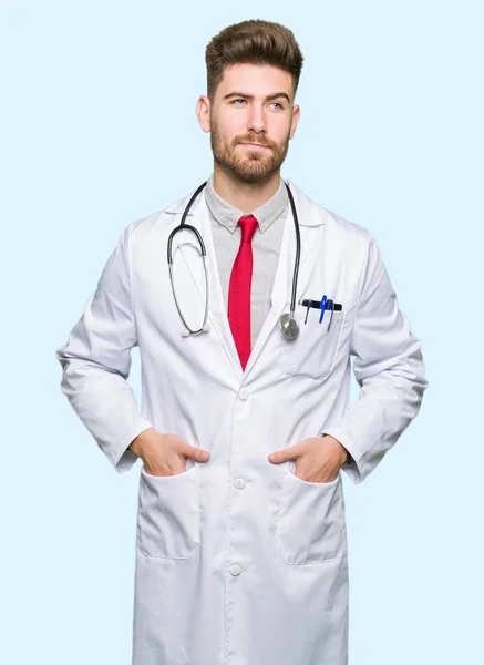 Joven Médico Guapo Hombre Con Abrigo Médico Sonriendo Mirando Lado —  Fotos de Stock