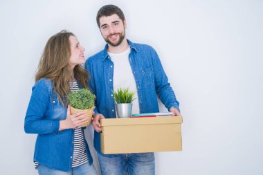 Beyaz izole arka plan üzerinde yeni bir eve taşımak için çok mutlu karton kutuları tutan genç güzel çift