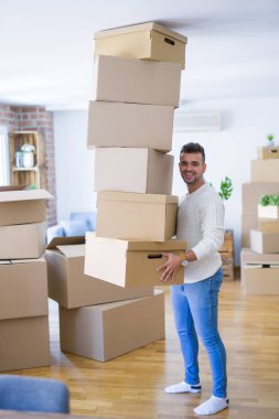 Genç yakışıklı adam yeni bir daireye hareket, karton kutular bir yığın tutan, yeni ev için mutlu