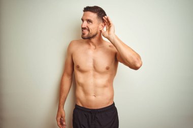 Tecrit edilmiş arka planda genç ve yakışıklı bir adam kulağına fısıldayarak dedikoduları ve dedikoduları dinliyor. Sağırlık kavramı.