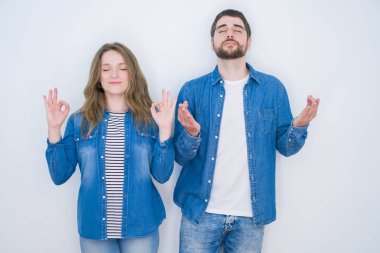 Genç güzel çift beyaz izole arka plan üzerinde birlikte duran dinlenmek ve gözleri parmakları ile meditasyon jest yapıyor kapalı gülümseyerek. Yoga konsepti.