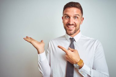 Soyutlanmış arka planda zarif beyaz gömlekler giyen genç yakışıklı iş adamı hayrete düşmüş ve kameraya gülümserken eliyle ve parmağıyla işaret ediyordu..