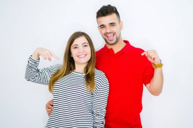 Genç güzel çift birlikte beyaz izole arka plan üzerinde yüzünde gülümseme ile emin görünümlü, parmakları gururlu ve mutlu kendini işaret.