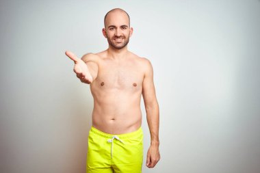 İzole edilmiş arka planda sarı mayo giyen, tatilde olan genç bir adam dostça bir selamlama ve hoş geldin hediyesi olarak gülümsedi. Başarılı bir iş..