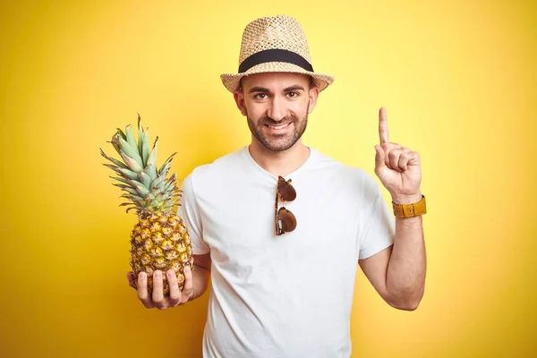 Jovem Usando Chapéu Verão Segurando Abacaxi Sobre Fundo Amarelo Surpreso — Fotografia de Stock