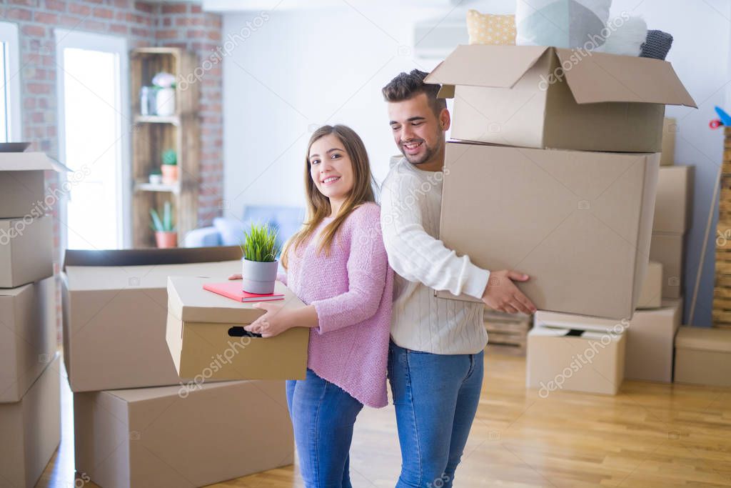 Young beautiful couple in love moving to new home, holding cardboard boxes very happy and cheerful for new apartment