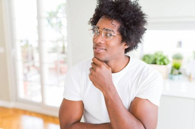 Afrika kökenli Amerikalı adam gözlüklü el ile çene düşünme hakkında soru, dalgın ifade üzerine. Düşünceli yüzüyle gülümsüyor. Şüphe kavramı.