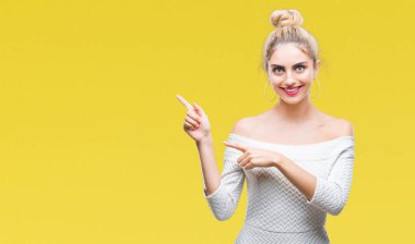 Genç güzel sarışın ve mavi gözlü kadın gülümseyerek ve iki elleri ve parmakları ile tarafına işaret kamera bakarak izole arka plan.