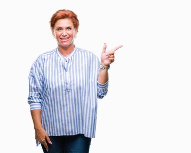 Yüzünde kocaman bir gülümseme ile izole arka plan Atrractive üst düzey beyaz Kızıl saçlı kadın kameraya bakarak yan el ve parmak ile işaret.