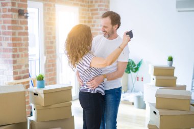 Orta yaş Senior çift yeni bir eve hareket, yeni bir ev metin ile bir tahta tutan Apartmant aşık mutlu gülümseyen