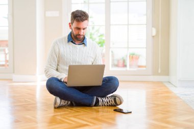 Yakışıklı adam akıllı yüzünde ciddi düşünme emin bir ifade ile bilgisayar dizüstü kullanarak giyen çalışma