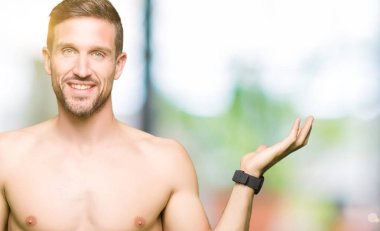 Gömleksiz yakışıklı gösteren çıplak göğüs neşeli sunulması ve kameraya bakarak avucunun ile işaret gülümseyen.