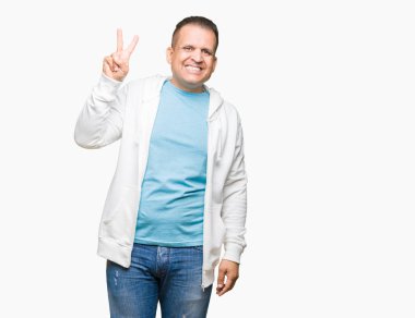 Gösterilen arka plan üzerinde sweatshirt giyen orta yaş Arap adam izole ve parmakları ile işaret kendinden emin ve mutlu gülümseyerek ise ikinci.