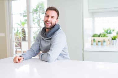 Evde rahat sweatshirt giyen ve olumlu gülümseyen yakışıklı adam