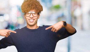 Afro yüzünde gülümseme ile kendinden emin görünüyorsun, kendini gururlu ve mutlu parmakları ile işaret gözlüklü genç yakışıklı adamla.