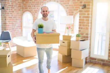 Genç yakışıklı adam yeni bir eve hareket, cardboxes SMIL tutarak