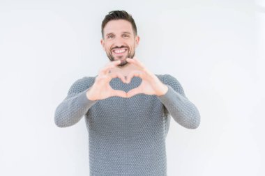 Genç yakışıklı adam izole arka plan üzerinde rahat kazak giyen sevgi kalp sembolü ve elleri ile şekil gösteren gülümseyerek. Romantik kavram.