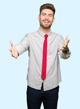 Genç yakışıklı iş adamı sarılmak için kollarını açarak gülümseyen kamera bakıyor. Neşeli ifade kucaklayan mutluluk.