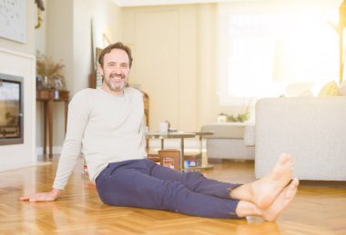 Evde kameraya gülümseyen katta oturan yakışıklı orta yaş adam