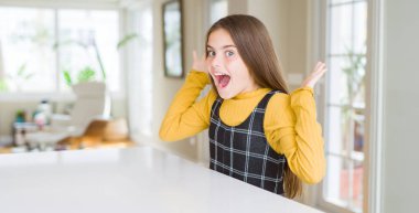 Güzel genç kız çocuk masada oturan deli kutluyor ve başarı için hayran silah kaldırdı ve açık gözleri heyecanlı çığlık. Kazanan kavramı