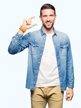 Sakal denim ceket gülümseyen ve boyutu işaret parmaklı ararken ve kamera işi el ile kendinden emin eller ve mavi gözlü yakışıklı adam. Ölçü kavramı.