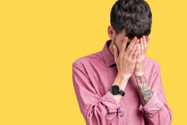 Yüzünü elleriyle ağlayarak süre kapsayan üzgün ifade ile izole arka plan üzerinde pembe gömlek giymiş yakışıklı delikanlı. Depresyon kavramı.