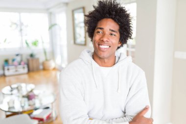 Afro-Amerikan erkek görünümlü yan ve dik dik bakma uzağa düşünce gülümseyen sweatshirt giyiyor.