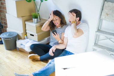Akıllı telefonu kullanarak yeni bir eve taşınan orta yaşlı çift, eliyle stresli, utanç ve sürpriz yüz, kızgın ve sinirli şok. Korku ve hata için üzgün.