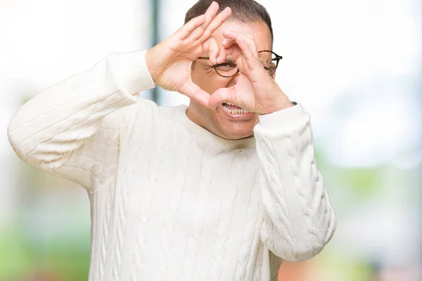 中年のアラブの男性は 孤立した背景の上に眼鏡をかけて サインを通して見ている手と指を使って心の形をしている — ストック写真