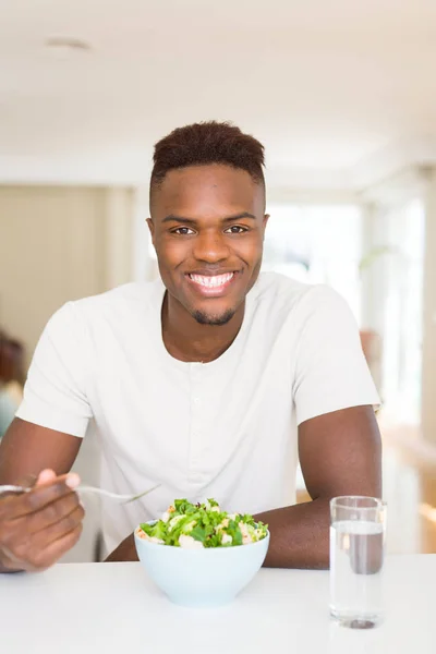 Knappe Afrikaanse jonge man het eten van een gezonde groente salade herstelle — Stockfoto