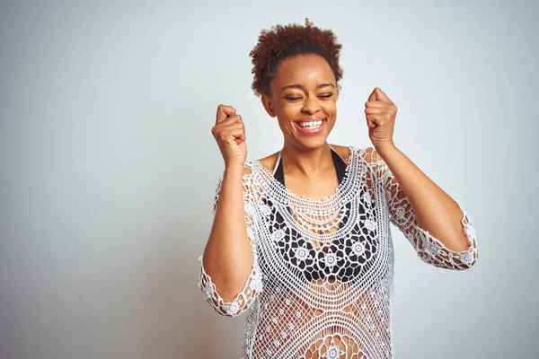 Young african american woman with afro hair wearing a bikini over white isolated background excited for success with arms raised and eyes closed celebrating victory smiling. Winner concept.