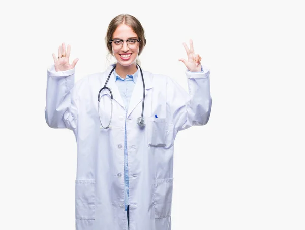 美丽的年轻金发碧眼的医生妇女穿着医疗制服在孤立的背景显示和手指指向八号 同时微笑着自信和快乐 — 图库照片