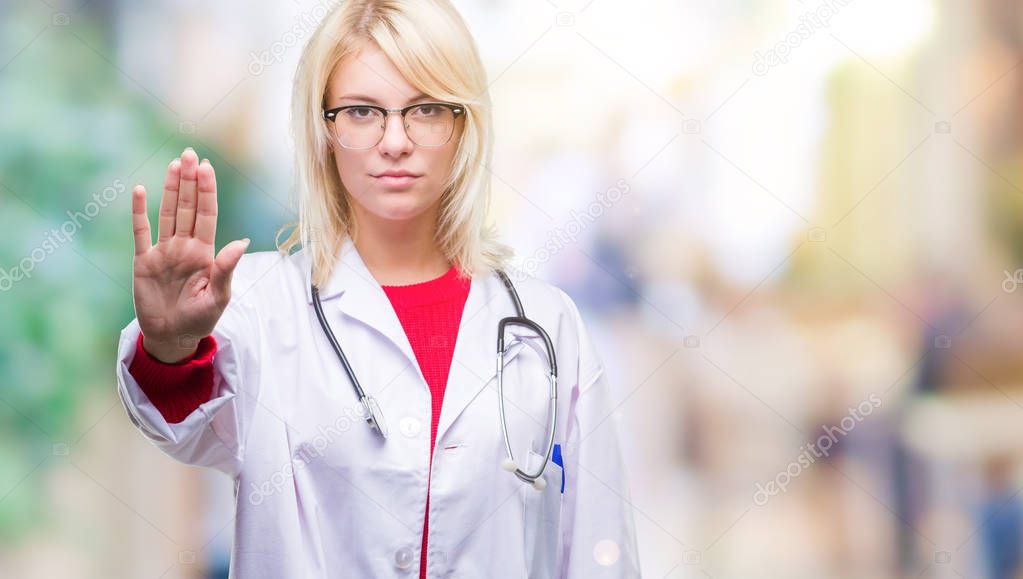 Young beautiful blonde doctor woman wearing medical uniform over isolated background doing stop sing with palm of the hand. Warning expression with negative and serious gesture on the face.