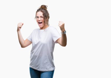 Güzel genç esmer kıvırcık saçlı kız üzerinde gözlük gülümseyen ve başarı için çığlık arka plan çok mutlu ve heyecanlı kaldırdı, silah ile kazanan jest yapıyor izole. Kutlama kavramı.