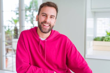 Evde rahat sweatshirt giyen ve olumlu gülümseyen yakışıklı adam