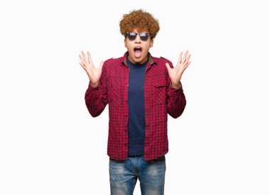 Yakışıklı genç afro saçlı deli kutluyor ve silah ile başarı için heyecanlı çığlık kaldırdı ve açık gözleri hayret güneş gözlüğü takıyor. Kazanan kavramı