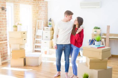 Güzel genç çift yeni bir eve hareket, karton kutular etrafında yeni Aparment ayakta, mutlu ve sevgi gülümseyen sarılmak