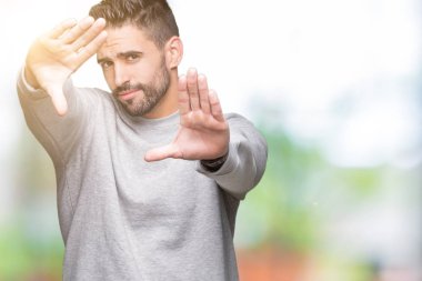 Genç yakışıklı adam giyen kazak izole üzerinde arka plan kullanarak el avuç içi ve parmaklar, kamera perspektif çerçevesini yapıyor gülen