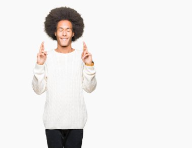 Afro saçlı genç afro-amerikalı adam kış kazak giyen umut ve gözleri kapalı ile geçiş parmakları gülümseyerek. Şans ve batıl kavram.