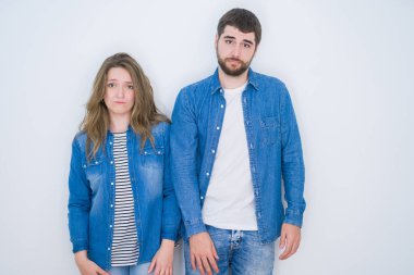 Genç güzel çift birlikte beyaz izole arka plan üzerinde ayakta depresif ve sıkıntı için endişe, kızgın ve korkmuş ağlıyor. Hüzünlü ifade.