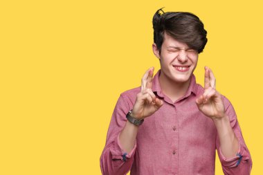 Genç yakışıklı iş adamı geçiş parmakları umut ve gözleri kapalı ile gülümseyen izole arka plan üzerinde. Şans ve batıl kavramı.