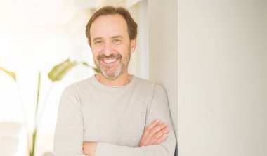 Evde kameraya bakarak gülümseyen yakışıklı orta yaş erkek