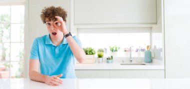 Evde ok jest yapan genç yakışıklı adam geniş çekim şaşırmış yüzü ile şok, göz parmaklarından bakarak. İnanmayan ifade.