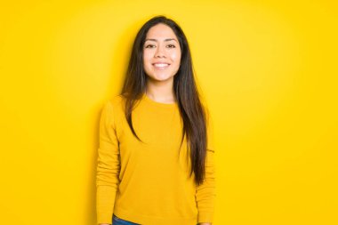 Sarı izole arka plan ile bir mutlu ve serin güzel esmer kadın yüzündeki gülümseme. Şanslı kişi.