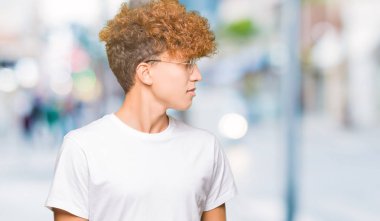 Yakışıklı genç afro saçlı gözlüklü uzak tarafına yüzünde, doğal ifade gülümseme ile seyir. Kendine güvenen gülüyor.