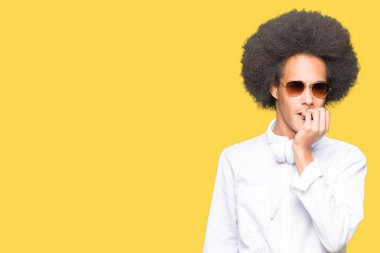 Afro saç güneş gözlüğü ve kulaklık giyen genç Afrikalı Amerikalı adam vurguladı ve ağız ısırma çivi elleri ile sinir bakıyor. Anksiyete sorunu.
