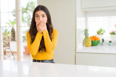 Beyaz masada evde genç güzel kadın hata elleri ile ağız kapsayan şok. Gizli konsept.